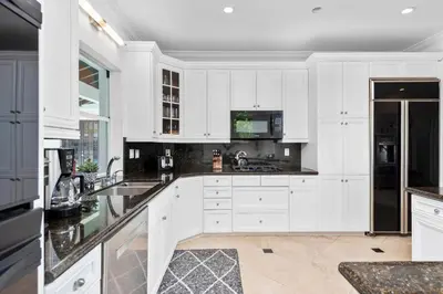 a kitchen with white cabinets and black appliances at Villa Asher - Waterfront with dock in Miami