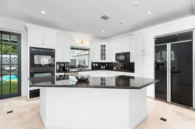 a kitchen with white cabinets and black appliances at Villa Asher - Waterfront with dock in Miami