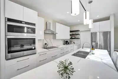a white kitchen with a sink and a stove top oven at Upscale 4 BDRM Retreat - Mins to Las Olas & Beach in Fort Lauderdale