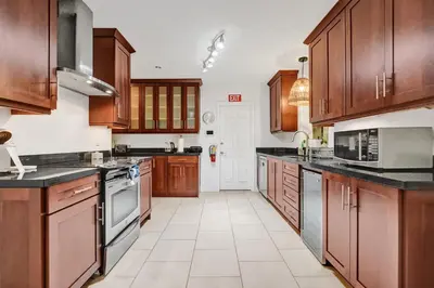 a large kitchen with wooden cabinets and black counter tops at Villa Calma Hidden Tropical Gem with Gym and Pool in Hollywood