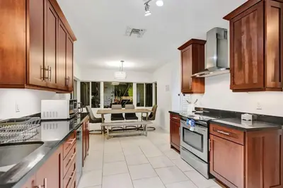 a kitchen with wooden cabinets and a living room at Villa Calma Hidden Tropical Gem with Gym and Pool in Hollywood