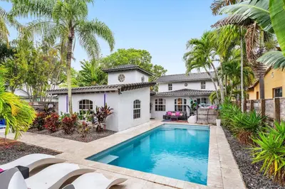 a swimming pool in front of a house with palm trees at Luxe 5BR 4BA I Heated Pool 10 Min to Beach I BBQ in Fort Lauderdale