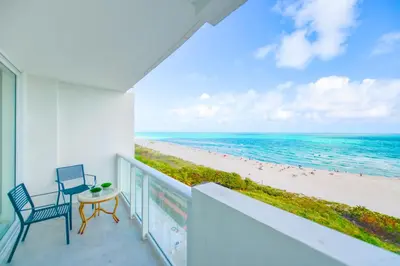 a balcony with a table and chairs and the beach at Ocean Breeze Retreat in Miami Beach in Miami Beach