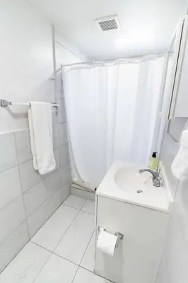 a white bathroom with a sink and a shower at Miami Shores Stay | Stylish Apt Minutes to Ocean in North Miami
