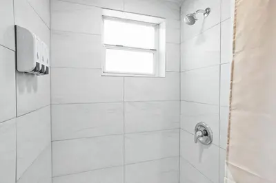 a white bathroom with a shower with a window at Miami Shores Stay | Stylish Apt Minutes to Ocean in North Miami