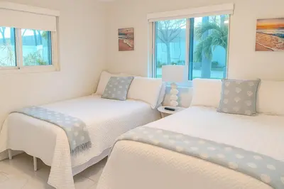 two beds in a room with two windows at Steps from Airport Hot Tub Bbq Boat Slip in Dania Beach