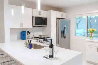 a white kitchen with two wine glasses on a counter at Steps from Airport Hot Tub Bbq Boat Slip in Dania Beach