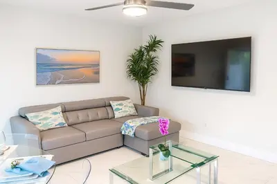 a living room with a couch and a flat screen tv at Steps from Airport Hot Tub Bbq Boat Slip in Dania Beach