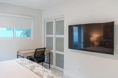 a bedroom with a large flat screen tv on a wall at Steps from Airport Hot Tub Bbq Boat Slip in Dania Beach