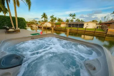 a jacuzzi tub in a backyard with a body of water at Waterfront HotTub Steps from the Airport Boat Slip in Dania Beach
