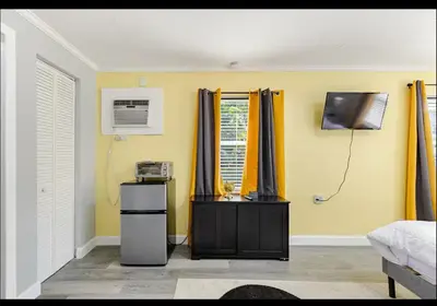 a bedroom with yellow walls and yellow curtains and a tv at Homeaway Haven in Fort Lauderdale
