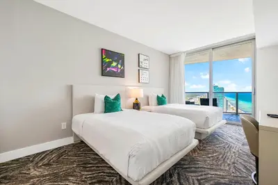 two beds in a room with a view of the ocean at Oceanfront Retreat Steps from Hollywood Beach in Hollywood