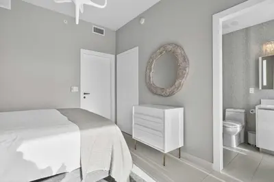 a white bedroom with a bed and a bathroom at Auberge Blue by Rove Travel Oceanfront with Balcony in Fort Lauderdale