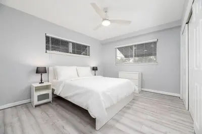 a white bedroom with a bed and two windows at The Residences at Lake Ridge Apt 1 in Fort Lauderdale