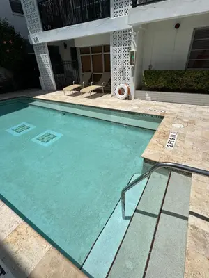 a swimming pool with chairs and a house at SOFI NEW! King Bed, Beach, BBQ, Gated! in Miami Beach