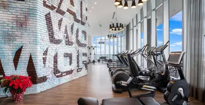 a gym with rows of treadmills and a brick wall at 39th Floor Oceanfront Penthouse with Pool & Gym in Hollywood