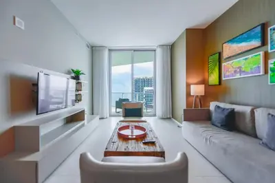 a living room with a couch and a tv at 39th Floor Oceanfront Penthouse with Pool & Gym in Hollywood