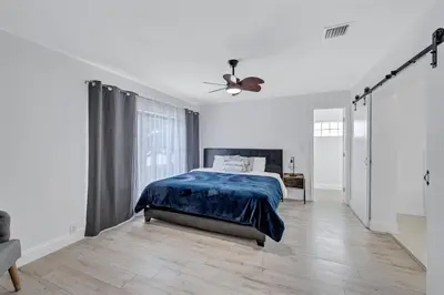 a white bedroom with a bed and a ceiling fan at Trendy Waterfront Pool Home Beach Casino Airport in Hollywood