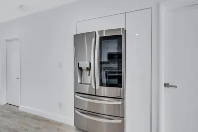 a stainless steel refrigerator in a white room at Trendy Waterfront Pool Home Beach Casino Airport in Hollywood