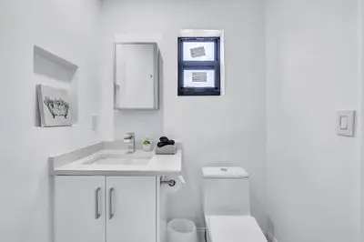 a white bathroom with a sink and a toilet at Trendy Waterfront Pool Home Beach Casino Airport in Hollywood