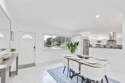a white kitchen with a table and chairs at Casa Moderna 3 Bed 2 Bath with Private Patio and BBQ in North Miami Beach