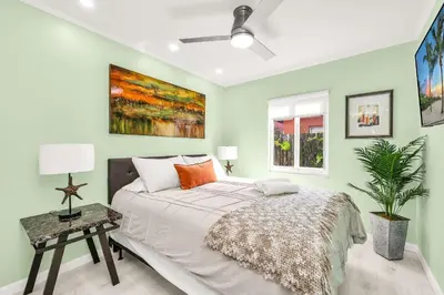 a bedroom with green walls and a bed with orange pillows at Backyard Oasis 3 Hole Golf Pool Fire Pit in Fort Lauderdale