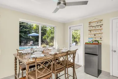 a dining room with a table and chairs and a refrigerator at Backyard Oasis 3 Hole Golf Pool Fire Pit in Fort Lauderdale