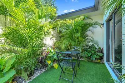 a patio with two chairs and palm trees at Chic Modern Studio with Queen Bed in Fort Lauderdale