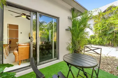 a patio with a table and chairs on the grass at Chic Modern Studio with Queen Bed in Fort Lauderdale