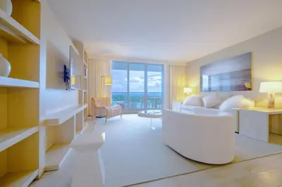a living room with a white couch and a room with a window at Amazing View 1 Hotel Corner Unit 1BR/1BA w Balcony in Miami Beach