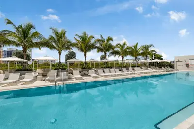 a swimming pool with lounge chairs and palm trees at Resort & Beach - The Ideal Condo at 72 Park in Miami Beach