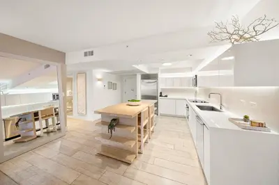a large kitchen with white cabinets and a wooden table at Oceanview Private Residence at 1 Hotel and Homes - 1202 in Miami Beach