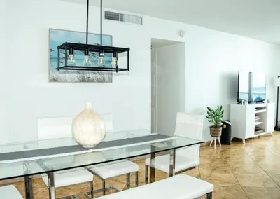 a dining room with a glass table and white chairs at The Azul Beachview Get away in Hollywood
