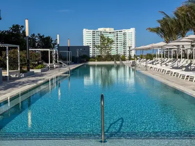 a large swimming pool with chairs and a building at Luxury View-Walk to beach! in Miami Beach