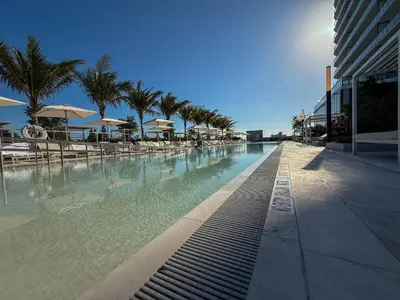 a swimming pool with chairs and umbrellas next to a building at Luxury View-Walk to beach! in Miami Beach
