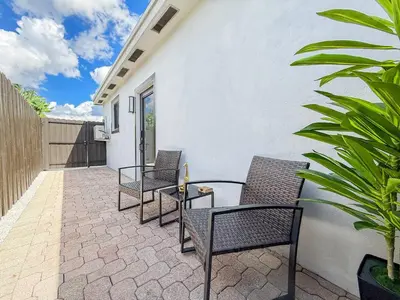 a patio with chairs and a table and a fence at Luxury Suite Studio with Kitchen & Spa Shower in Miramar