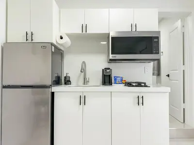 a kitchen with white cabinets and a stainless steel refrigerator at Luxury Suite Studio with Kitchen & Spa Shower in Miramar