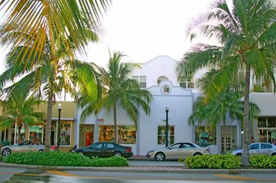 a white building with palm trees in front of it at Best Location In South Beach Steps To Everything! in Miami Beach