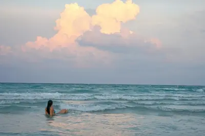 a woman sitting in the water on the beach at Best Location In South Beach Steps To Everything! in Miami Beach