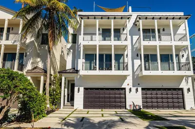a white building with two garage doors and a palm tree at Walk to Hollywood Beach Luxury Family Getaway! in Hollywood