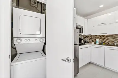 a kitchen with white cabinets and a refrigerator at Sleek Kitchenette & Queen Bed in Fort Lauderdale
