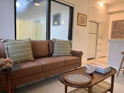 a living room with a brown couch and a table at The Modern Oasis Queen Studio with Kitchen in Fort Lauderdale