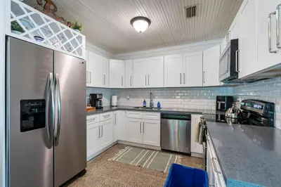 a kitchen with white cabinets and a stainless steel refrigerator at Jungle Fortress in Fort Lauderdale