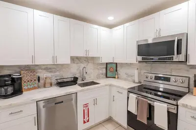 a kitchen with white cabinets and a stove and microwave at Villa Hollywood Pool Trampoline BBQ Hard Rock in Hollywood