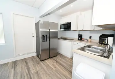 a kitchen with a stainless steel refrigerator and white cabinets at Coastal Collection in Fort Lauderdale