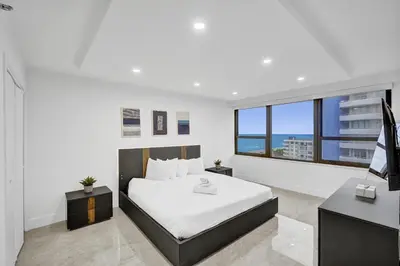 a bedroom with a bed and a desk and a television at Modern 3BR Ocean view Condo with Pools, Gym and Sauna 1407 in Miami Beach