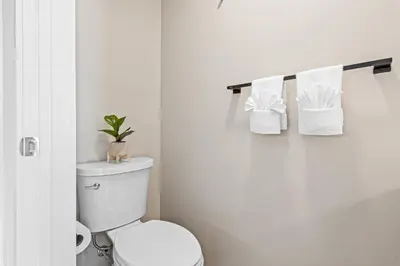 a white bathroom with a toilet and towels at 72 Park Condo - City Views & Prime Location in Miami Beach