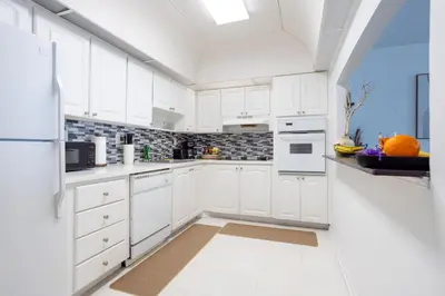 a white kitchen with white cabinets and white appliances at 1-Bedroom Apartment with Ocean View and Balcony near Sunny Isles Beach in Sunny Isles Beach