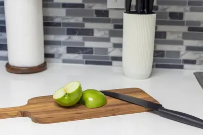 a cutting board with two green apples and a knife at 1-Bedroom Apartment with Ocean View and Balcony near Sunny Isles Beach in Sunny Isles Beach