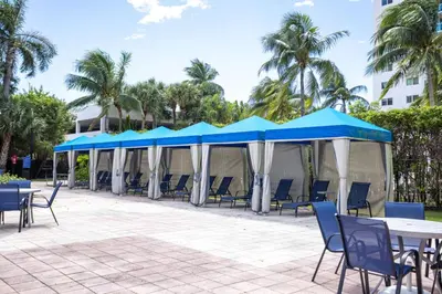 a group of blue and white umbrellas and tables and chairs at 1-Bedroom Apartment with Ocean View and Balcony near Sunny Isles Beach in Sunny Isles Beach
